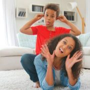 Portrait Of Mother And Son Lying On Rug And Pulling Faces At Home