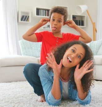 Portrait Of Mother And Son Lying On Rug And Pulling Faces At Home
