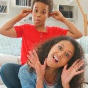 Portrait Of Mother And Son Lying On Rug And Pulling Faces At Home